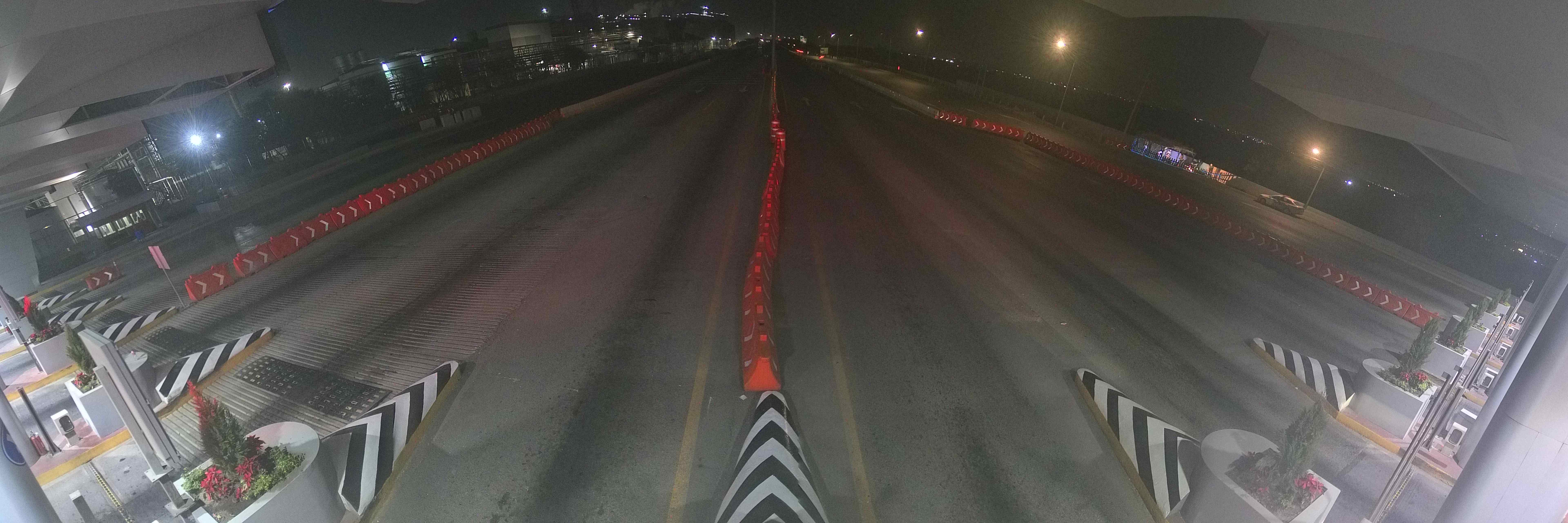 An empty toll plaza at night, lanes stretching into darkness, red reflectors down the dividers, not a single car.